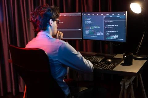 Working IT developer concentrating online software at neon light room. Gusher. Stock Photos