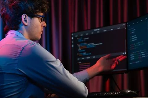 Working IT developer concentrating online software at neon light room. Gusher. Stockfoto's