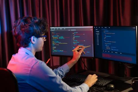 Working IT developer concentrating online software at neon light room. Gusher. Stockfoto's