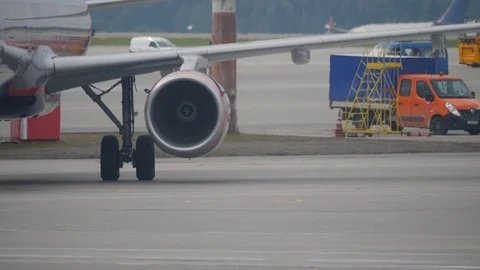 Working jet engine and landing gear of a jetliner moving on airport apron Stock Footage 94513774