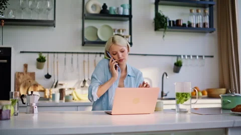 Working lady calling cellphone at kitchen closeup. Happy girl typing laptop Stock Footage 335151504