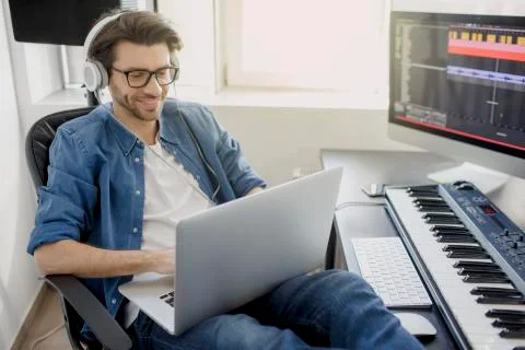 Working on a laptop. Busy guy. Multitasking concept. DJ in broadcasting studio Stock Photos