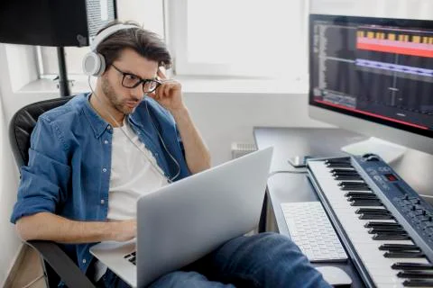 Working on a laptop. Busy guy. Multitasking concept. DJ in broadcasting studio Stock Photos