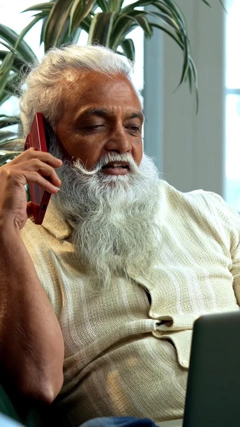 Working on laptop during phone call, mid age Indian man reviewing reports Stock Footage 342757122