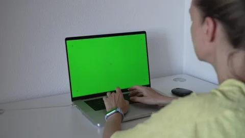 Working on a laptop with a green screen in a simple room during the day Stock Footage 340190019