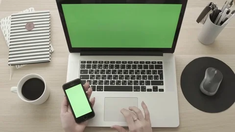 Working on laptop using touch pad and holding smartphone, green screen Stock Footage 83417508