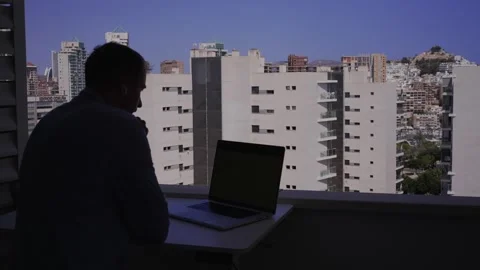 Working at a laptop while looking out at a city skyline on a clear day in a.. Stock Footage 340189688