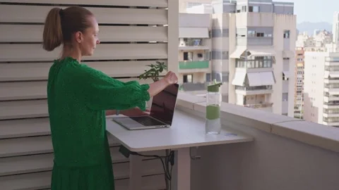 Working on a laptop while standing at a table on a balcony overlooking the .. Stock Footage 340193377