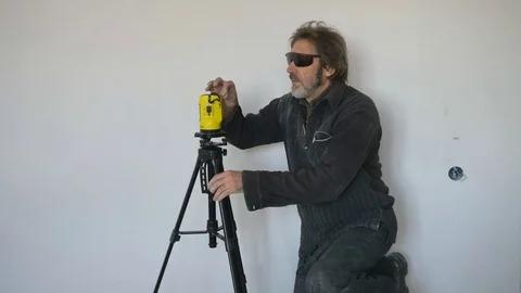 Working with a laser level makes markings on the wall. Mechanical lifting Stock Footage 74764464