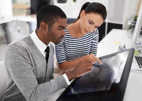 Working with the latest tech. two designers using a large touchscreen monitor. Stock Photos