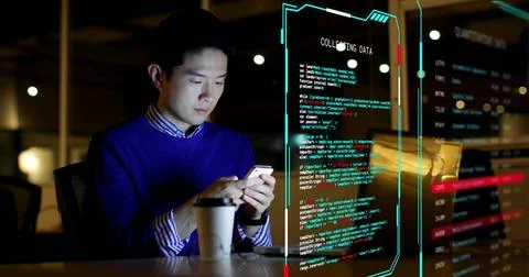 Working man in blue sweater checking phone at office with laptop, coffee, code 스톡 사진