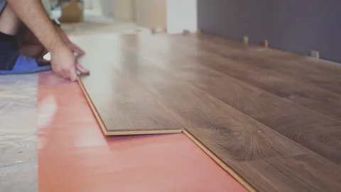 Working man installing laminate flooring in the house and connecting the Video stock 142608266