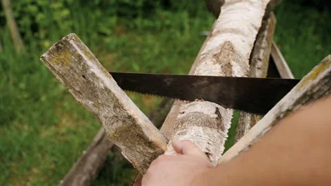 A working man is sawing wood with a saw. Summer. Green grass in the yard Vídeos de archivo 132407853