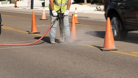 Working man uses a jackhammer on the asphalt of a city street for utilities Stock Footage 127936154