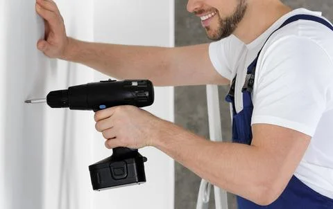 Working man using electric screwdriver indoors, closeup. Home repair Stock Photos