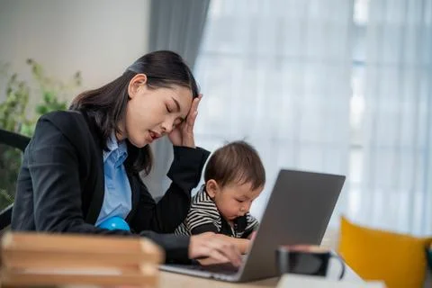Working mother struggles to focus on tasks while caring for toddler at home.. Stock Photos