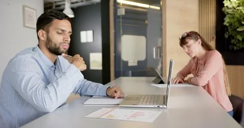 Working in office, man using laptop and writing in notepad at desk Foto stock