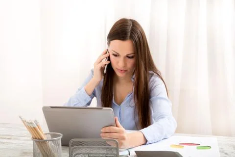 Working at the office, using the tablet and talking by phone Stock Photos