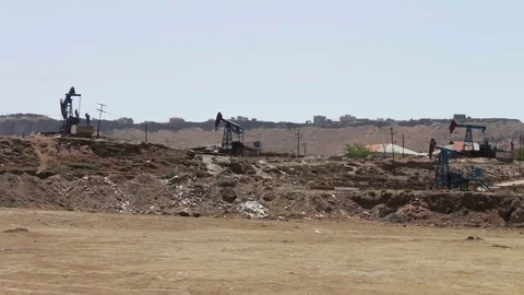 Working oil pump and an old rusty iron barrel near on a background of blue sky Stock Footage
