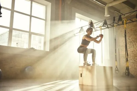 Working out. Side view of beautiful athletic woman in sportswear training legs Stock Photos
