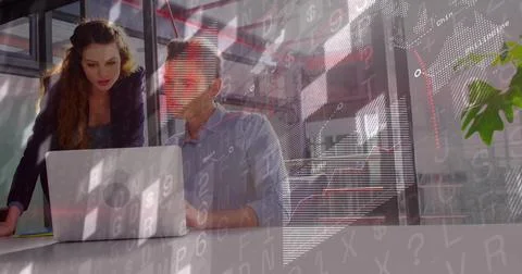 Working pair wearing dark blazer, light shirt leaning over laptop in glass room, Fotos Stock