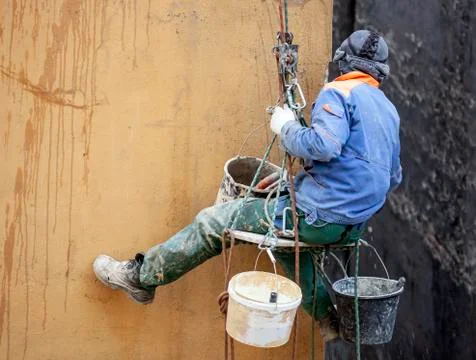 Working plasterer on the wall of the house working with climbing equipment. Foto stock