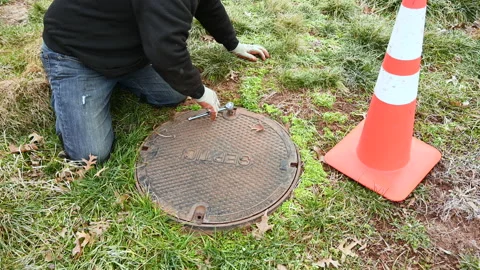 A working plumber opening septic system tank, unscrewing nuts to Inspection.. Stock Footage 238565380