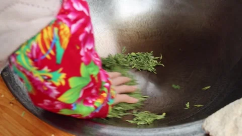 Working pressing longjing tea leaves in a pan to flatten the leaves as second Video stock 315370499