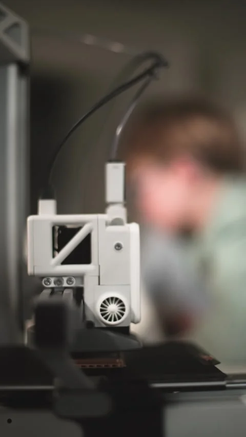 Working print head of a 3D printer, in the background are kids Stock Footage 335396618
