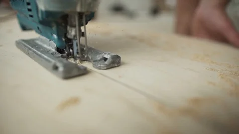 Working process of green dusty electric jigsaw cutting wooden flat board. Stock Footage 99614323
