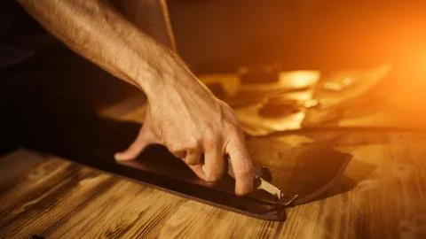 Working process of the leather belt in the leather workshop. Man holding tool Stock Photos