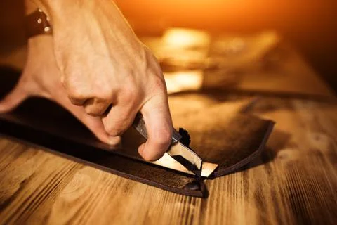 Working process of the leather belt in the leather workshop. Man holding tool Stock Photos