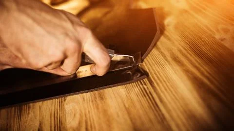 Working process of the leather belt in the leather workshop. Man holding tool Stock Photos