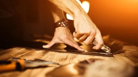 Working process of the leather belt in the leather workshop. Man holding tool Stock Photos