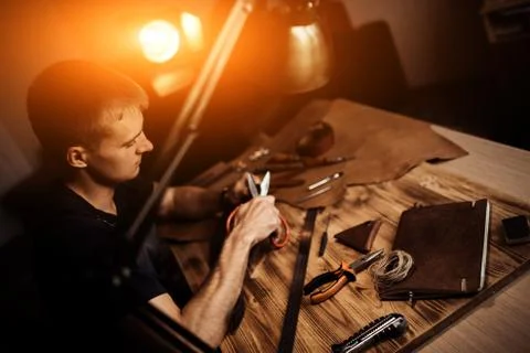 Working process of the leather belt in the leather workshop. Man holding Stock Photos