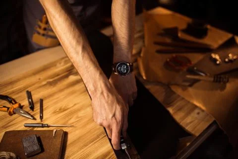Working process of the leather belt in the leather workshop. Man holding Stock Photos
