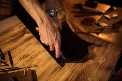 Working process of the leather belt in the leather workshop. Man holding Stock Photos