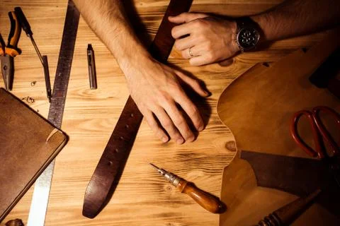 Working process of the leather belt in the leather workshop. Man holding hands Stock Photos