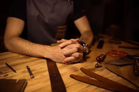 Working process of the leather belt in the leather workshop. Man holding hands Stock Photos