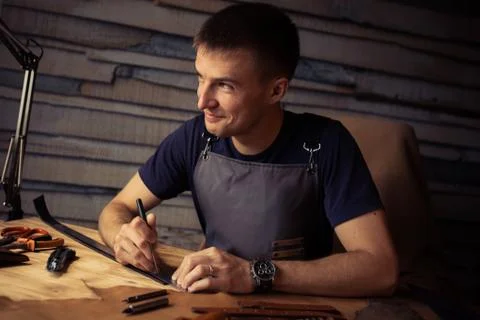Working process of the leather belt in the leather workshop. Man holding Stock Photos