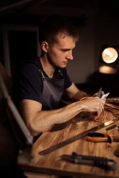 Working process of the leather belt in the leather workshop. Man holding Stock Photos