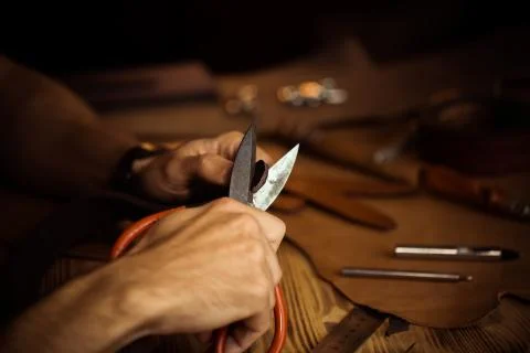 Working process of the leather belt in the leather workshop. Man holding Stock Photos