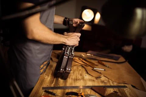 Working process of the leather belt in the leather workshop. Man holding Stock Photos
