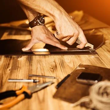 Working process of the leather belt in the leather workshop. Man holding Stock Photos