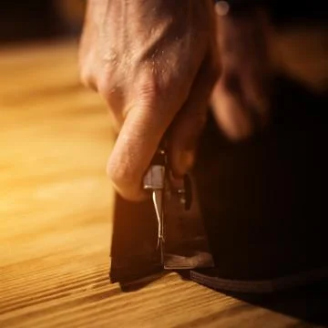 Working process of the leather belt in the leather workshop. Man holding Stock Photos