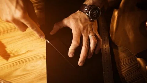 Working process of the leather belt in the leather workshop. Man holding tool Stock Photos