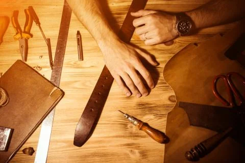 Working process of the leather belt in the leather workshop. Man holding hands Stock Photos