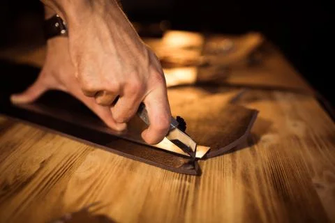 Working process of the leather belt in the leather workshop. Man holding Stock Photos