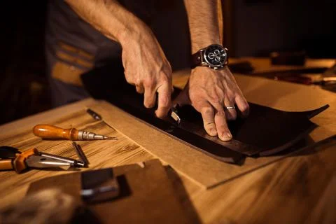 Working process of the leather belt in the leather workshop. Man holding Stock Photos