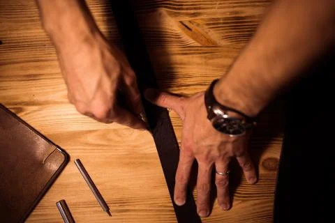 Working process of the leather belt in the leather workshop. Man holding Stock Photos
